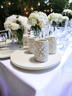 the table is set with white flowers and wine glasses