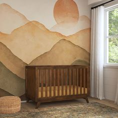 a baby crib in front of a wall with mountains painted on it and a rug