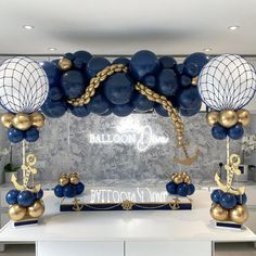 a table topped with blue and gold balloons in the shape of an anchor, globes and other decorations