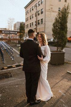 a bride and groom are standing in the street