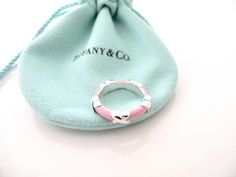 Overview:Everyone needs a signature Tiffany piece! Here is the ultimate Tiffany Signature piece just for you! Offered for sale is a wonderful and mint Tiffany & Co. Sterling Silver and Pink Enamel Signature Ring. The piece is crafted from bright and substantial Tiffany silver, and yet retains a feminine and delicate feel to it. It is a wonderful ring that fits a lifestyle on the go -- can be worn to almost any occasion! It is simple, elegant, and classic all rolled into one item. Imagine the pie Signature Ring, X Ring, Signature Rings, Pink Enamel, Gift Pouch, Ring Band, Love Gifts, Tiffany & Co., Band Rings