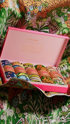 a pink box filled with lots of different colored donuts