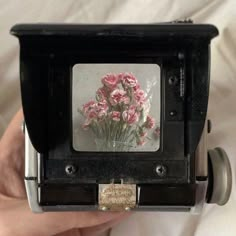 a person is holding up an old fashioned camera with pink flowers on the front and side