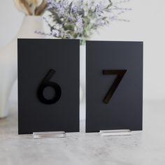 the number seven is placed next to a vase with flowers in it on a table