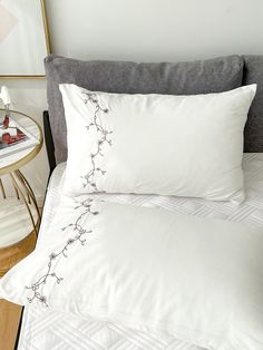 a bed with white sheets and pillows on top of it next to a side table