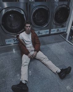 a man sitting on the ground in front of washing machines