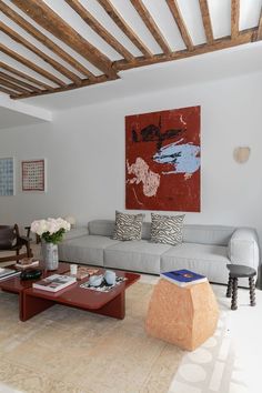 a living room with couches, coffee table and paintings on the wall