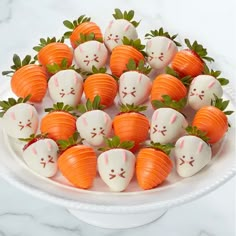 a white plate topped with lots of chocolate covered strawberries and carrots in the shape of rabbits