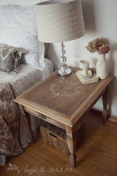 a bed room with a neatly made bed and a night stand next to a lamp