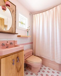 a bathroom with a pink toilet and sink next to a shower curtain in the corner