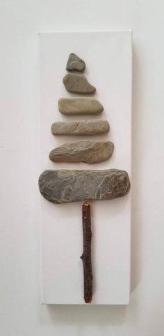 a piece of art made out of rocks with a hammer stuck in the middle and a rock stack on top