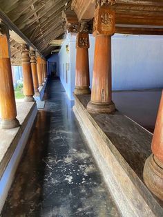 the walkway is lined with wooden pillars and stone flooring, along with white walls