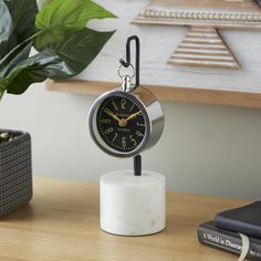 a clock sitting on top of a table next to a potted plant and books