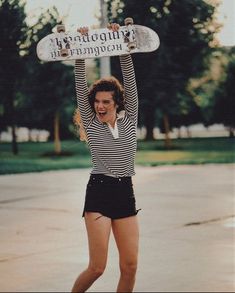 a woman holding up a skateboard above her head