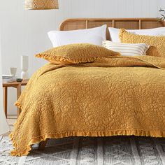 a bed with yellow bedspread and white pillows