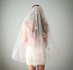 the back of a woman wearing a wedding veil with flowers on it's head