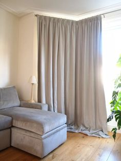 a living room with a gray couch and white curtains