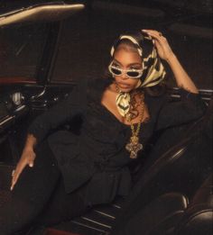 a woman sitting in the backseat of a car wearing sunglasses and a scarf around her head