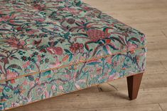 an upholstered footstool with flowers and leaves in blue, pink, green, orange and red colors