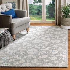 a living room with a couch, chair and rug on the hardwood floor next to sliding glass doors