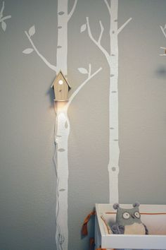 a baby's room with a white tree wall decal and a birdhouse