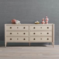 a white dresser sitting on top of a hard wood floor next to a gray wall