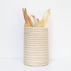 a white ceramic vase filled with corn on the cob