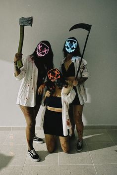 three women in costumes with masks on their faces and one holding an ax, while the other holds a sculler