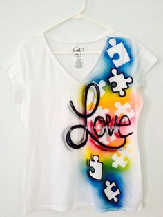 a t - shirt with the word love painted on it and puzzle pieces hanging from a hanger