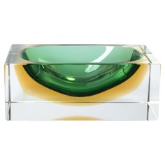 a green and yellow glass bowl sitting on top of a clear box with a white background