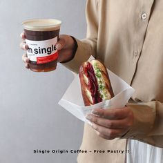 a person holding a sandwich and a cup of coffee in their hands, with the caption single origin coffee - free pastry