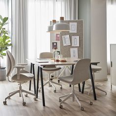 a white table and chairs in a room with wood flooring, large windows and pictures on the wall