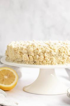 a cake with crumbs is on a white plate next to some lemon slices