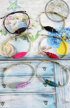 several different types of bracelets are sitting on top of an old dresser with flowers and seashells