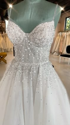 a white dress with silver sequins is on display in a store window,