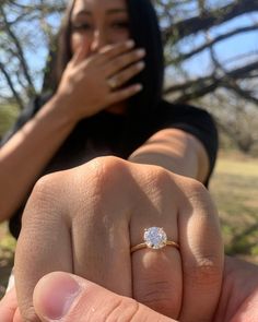 a woman holding her hand up to the camera with a diamond ring on it's finger