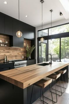 a modern kitchen with black cabinets and wooden counter tops, along with stools that match the hardwood flooring