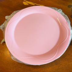 a pink plate sitting on top of a wooden table