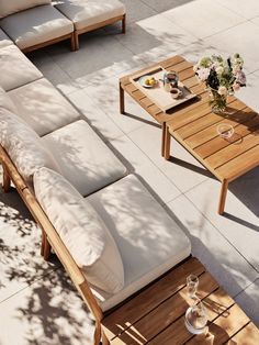 a wooden table sitting on top of a patio next to a couch and coffee table