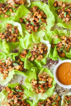 lettuce cups filled with chicken and sauce on a tray next to dipping sauce