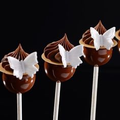 four chocolate lollipops with white butterflies on them sitting on top of each other