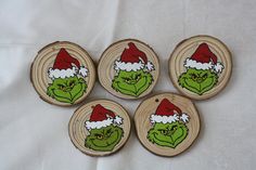 four wooden coasters with the grin face painted on them and santa's hat