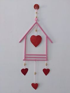 a pink and red house with hearts hanging from it's side on a white wall