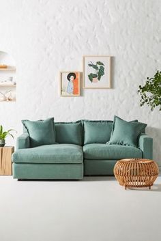 a living room with white walls and green furniture in the corner, including a large sectional couch