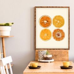 an orange print hangs on the wall above a table with two cups and saucers