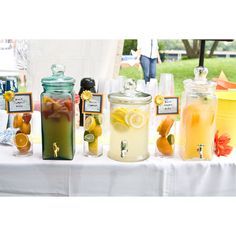 a table topped with jars filled with different types of drinks and lemons on top of it