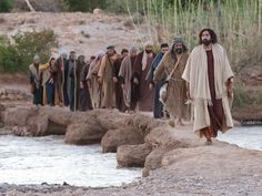 a group of people walking across a river