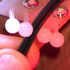 a person holding a cell phone with two ear plugs attached to the back of it