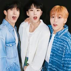 three young men standing next to each other in front of a black background, one with his tongue out