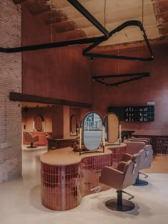 the interior of a hair salon with chairs and mirrors on the wall, along with brick walls